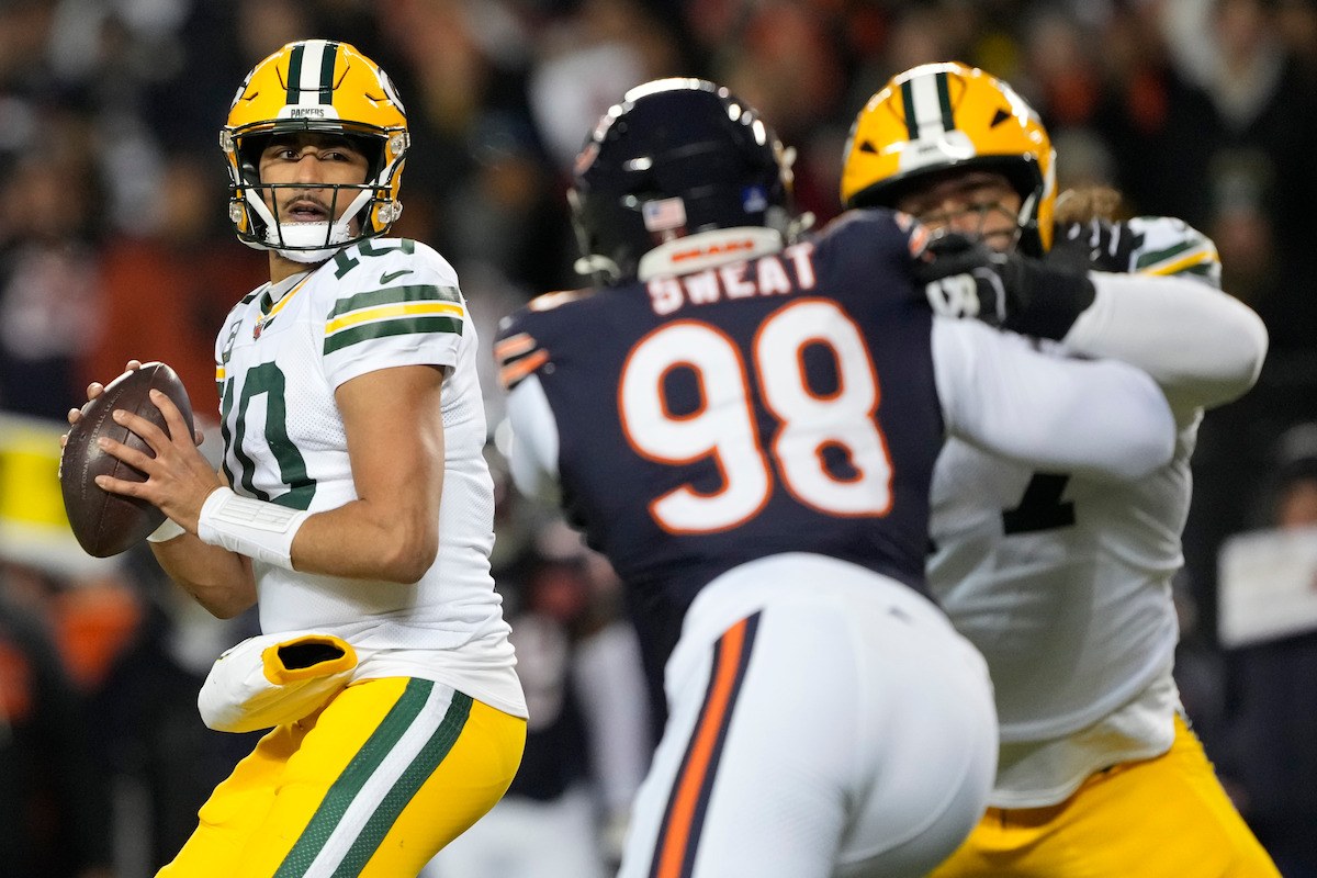 Green Bay Packers quarterback holding the ball as a Chicago Bears defender closes in